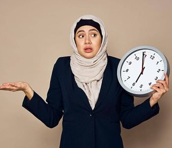 pngtree-a-hijabclad-woman-holding-a-clock-while-working-in-an-office-with-a-beige-background-photo-image_40036650